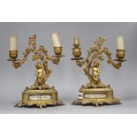 A pair of French gilt metal two light candelabra, modelled with putti seated beneath vine branches