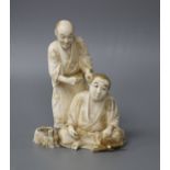 A Japanese Meiji period ivory okimono carved with a doctor treating a man's ear, signed, height 12cm