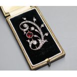 An early 20th century yellow and white metal, natural red spinel and diamond set foliate scroll