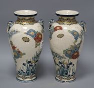 A pair of Satsuma vases, decorated with chrysanthemums, irises and storks, with beast head lug