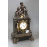 A Victorian bronze mounted black slate mantel clock, with enamelled dial, surmounted with figures of