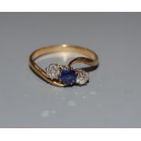 A yellow metal, sapphire and diamond three stone crossover ring, size O, gross weight 2.3 grams.