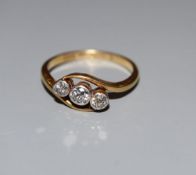 An 18ct and Pt, three stone diamond crossover ring, size M/N, gross 3 grams.CONDITION: One of the