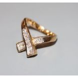 A modern 585 yellow metal and diamond set 'X' ring, size H, gross 4.3 grams.CONDITION: Two of the
