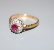 A mid 20th century yellow metal (stamped 18ct and Plat), ruby and diamond cluster ring, size L/M,