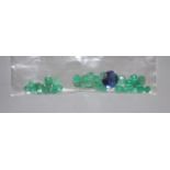 Approximately twelve carats of unmounted round cut emeralds and a round cut synthetic sapphire.