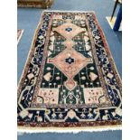 A Turkish rug, dark blue/brown ground centred by a rose pink double lozenge, 267 x 142cm