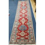 A Caucasian style red ground runner, 307 x 80cm