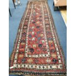 A Gendje red ground runner, c.1900, with polychrome field of stylised pears and multi row border,