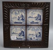 Four blue and white Delft tiles, housed in a carved oak frame, overall 35cm sq.