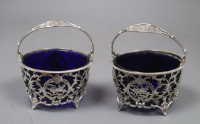 A matched pair of early 20th century pierced silver circular baskets, with blue glass liners, Horton