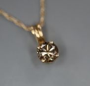 A 10k and 'chocolate' colour round brilliant cut solitaire diamond pendant, on a 10k fine link chain
