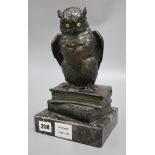 An early 20th century German bronze of an owl, with glass eyes, perched on a stack of two books,