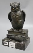 An early 20th century German bronze of an owl, with glass eyes, perched on a stack of two books,