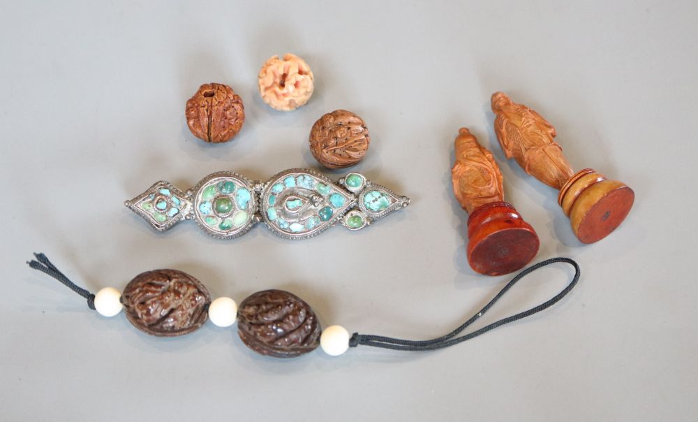 A group of Chinese nuts or wood carvings of deities, a turquoise mounted brooch and various beads
