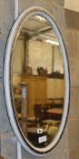 An oval white painted silvered frame bevelled wall mirror, W.72cm, H.47cm