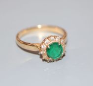 A yellow metal, emerald and diamond circular cluster ring, size L/M, gross 3.1 grams.CONDITION: