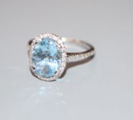 A modern aquamarine and diamond set oval dress ring, with diamond set shoulders, 18ct white gold