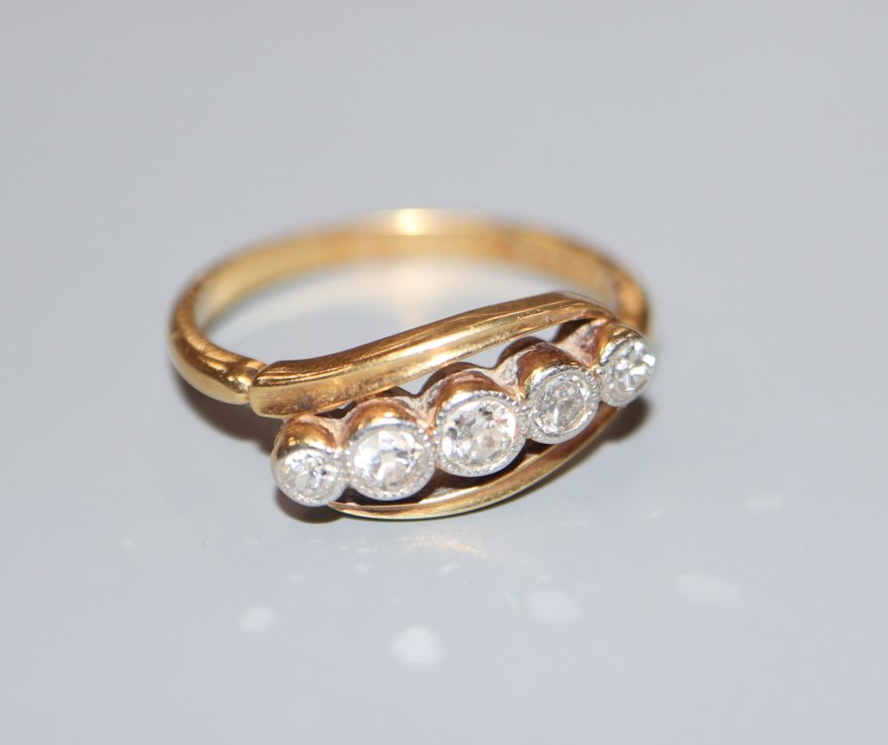 An 18ct and Plat, graduated five stone diamond set crossover ring, size K, gross 2.9 grams.