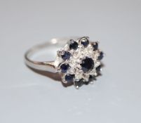 A modern 18ct white gold, sapphire and diamond cluster ring, size S, gross 4.7 grams.CONDITION: