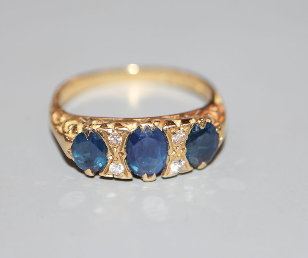 A 1970's Victorian style 18ct gold and three stone sapphire and diamond chip set dress ring, size L,