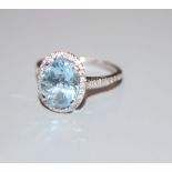 A modern aquamarine and diamond set oval dress ring, with diamond set shoulders, 18ct white gold