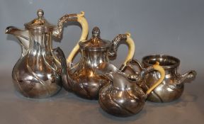 An early 20th century continental white metal four piece tea set, three with carved ivory handles,