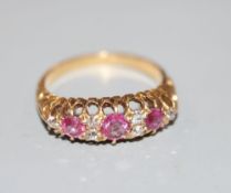 An early 20th century 18ct and graduated three stone ruby and diamond chip set half hoop ring,