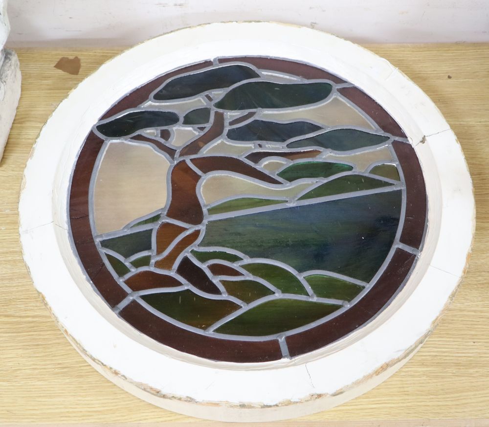 An Art Deco circular stained glass panel depicting a tree, housed in a painted wood frame, overall