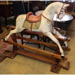 An early 20th century Ayres type carved wood dapple grey rocking horse on pine safety frame, H.
