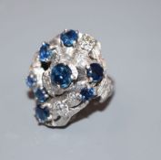 A 1970's? textured 18ct, sapphire and diamond cluster dress ring, in a raised setting, size P, gross