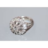 An 18ct and plat, diamond cluster ring, in a raised setting, size J, gross weight 6.7 grams, set