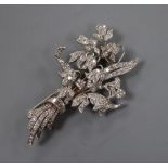 A white metal (tests as 18ct) and graduated baguette and round cut diamond set floral spray clip