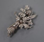 A white metal (tests as 18ct) and graduated baguette and round cut diamond set floral spray clip