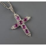 A white metal, six stone pink sapphire and diamond chip set cross pendant, with diamond set bale,