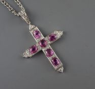 A white metal, six stone pink sapphire and diamond chip set cross pendant, with diamond set bale,