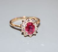 An 18k, ruby and diamond set oval cluster ring, size L, gross 2.9 grams.CONDITION: One of the