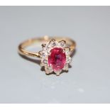 An 18k, ruby and diamond set oval cluster ring, size L, gross 2.9 grams.CONDITION: One of the