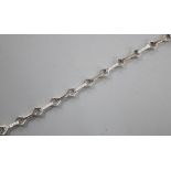 A modern 18k and diamond chip set baton and diamond shaped link line bracelet, 17.5cm, gross 9.5