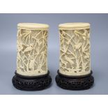 A pair of Japanese carved and pierced ivory brush pots, on hardwood stands, height 20cm