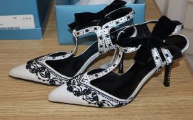 A pair of white satin with black beading Karen Miller T strap shoes with black velvet bows and