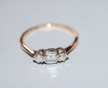 A yellow metal and three stone diamond ring, with central rectangular stone, size M, gross 1.6