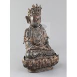 A Chinese lacquered bronze seated figure of Guanyin, possibly Ming dynasty, holding a ewer in both