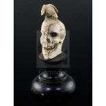 A 19th century Dieppe carved bone memento mori, with a bird perched upon a part fleshed skull, on