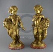 A pair of ormolu figures of putti holding flowers and a sickle, standing upon naturalistic