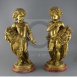 A pair of ormolu figures of putti holding flowers and a sickle, standing upon naturalistic