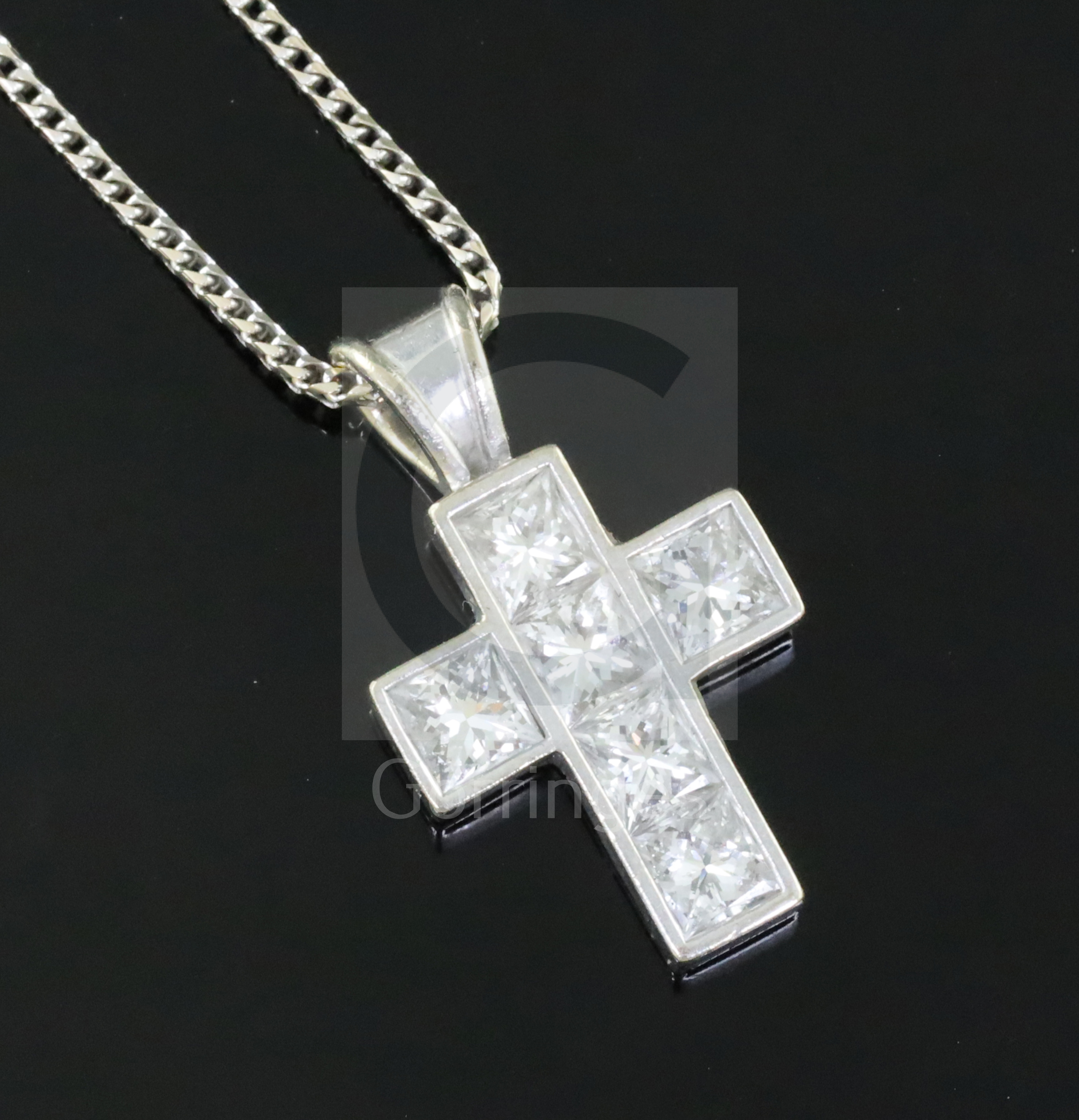 A modern 18ct white gold and six stone Princess cut diamond set cross pendant by Theo Fennell, on an