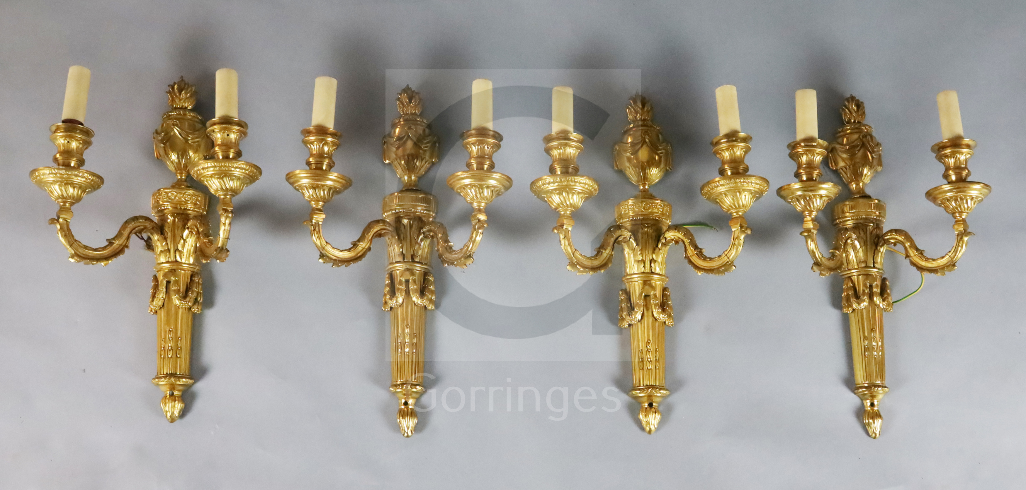 A set of four Adam revival ormolu twin branch wall lights, with flaming urn backplates and foliate