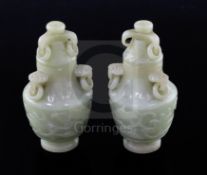 A pair of Chinese carved jade vases and covers, with ring handles and decorated with foliate motifs,