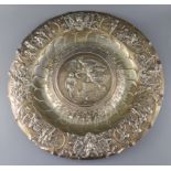 A large embossed white metal charger, decorated with musical trophies, masks and classical figures